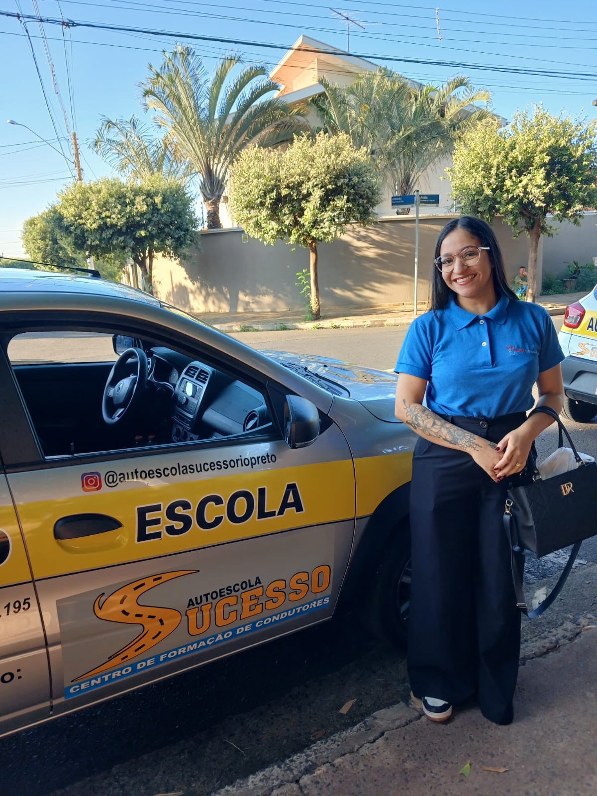 Aluna aprovada segurando sua CNH em frente ao carro da autoescola